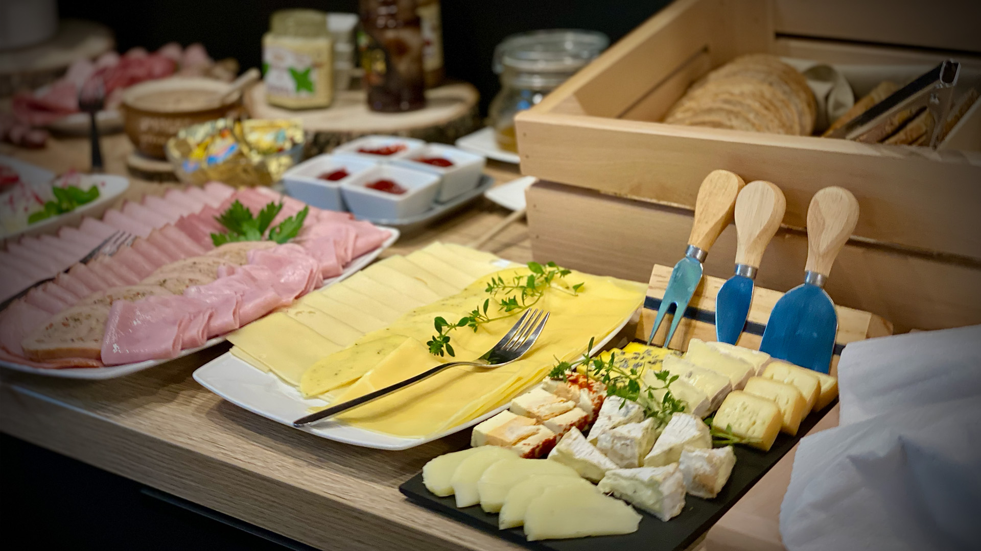 Deska serów, wędliny i świeże pieczywo na bufecie śniadaniowym